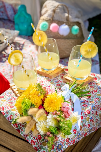 Limonadas, comida y flores en un picnic.