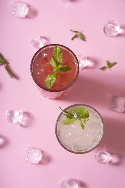 Limonadas de verão com gelo e hortelã em copos de vidro vista superior em fundo rosa