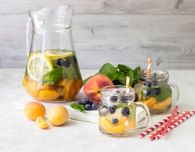 Limonade aus Aprikosen, Heidelbeeren und frischer Minze in Gläsern.