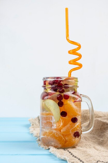 Limonade mit Cranberry und Zitrusfrüchten auf blauem Hintergrund.
