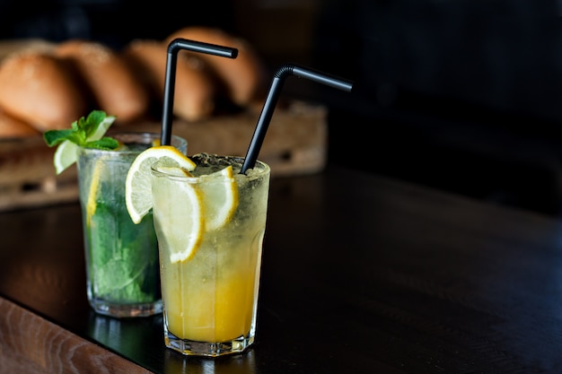 Limonade mit Zitrone und Minze auf dem Hintergrund von frisch gebackenen Brötchen im Café. Sommergetränk