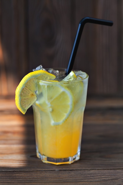 Foto limonade mit zitrone und sirup auf einem holztisch. sommergetränk