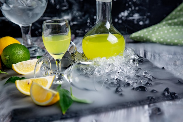 Limoncello digestivo típico italiano con limones frescos en humo, enfoque selectivo.