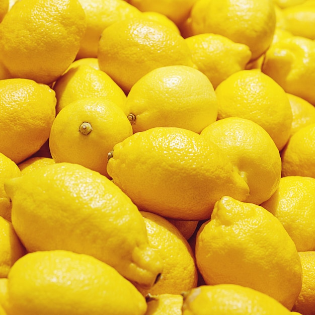 Limones amarillos de cerca en el mercado de frutas, fondo de limón brillante