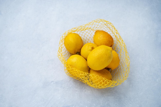 Limones amarillos frescos en una bolsa de plástico sobre un fondo de textura azul El concepto de alimentación saludable Vista superior y espacio de copia