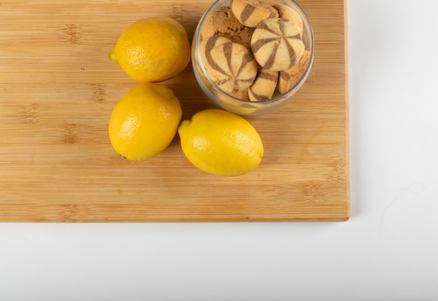 Limones amarillos y galletas en una taza. vista superior