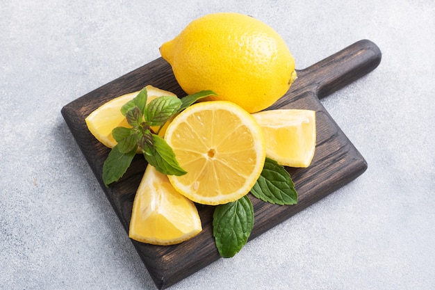 Limones amarillos jugosos enteros y cortados con hojas de menta fresca