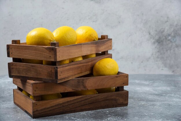 Limones en caja de madera sobre fondo gris