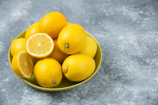 Limones en caja de tazón de madera sobre fondo gris