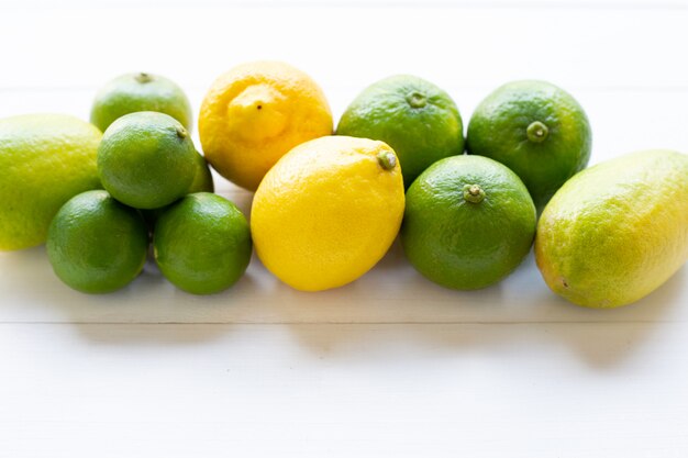 Limones y cales maduros sobre madera blanca.