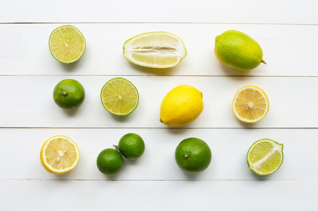 Limones y cales maduros sobre madera blanca.