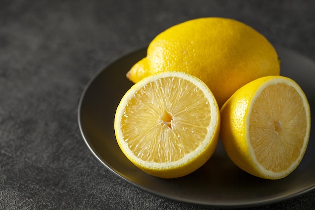 Limones enteros y cortados en el enfoque selectivo de fondo oscuro de la placa