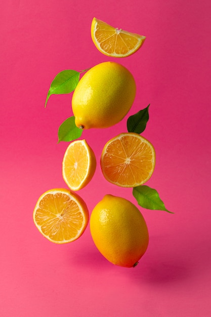 Limones flotando en el aire contra rosa brillante