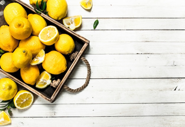 Limones frescos en una bandeja. Sobre una mesa de madera blanca.