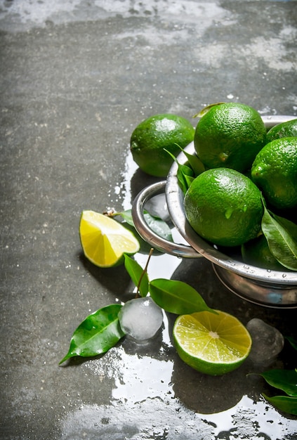 Limones frescos en una cacerola con rodajas y hojas alrededor.