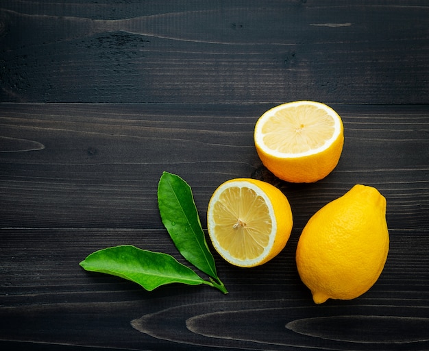 Limones frescos y hojas de los limones en el fondo de madera oscuro.