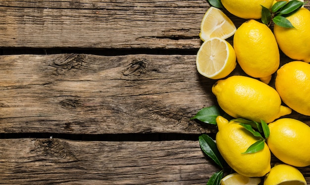 Limones frescos con hojas sobre fondo de madera