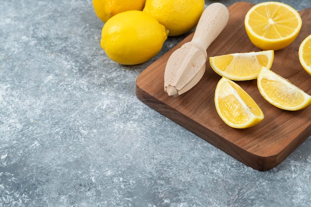 Limones frescos y en rodajas sobre tabla de cortar de fondo gris