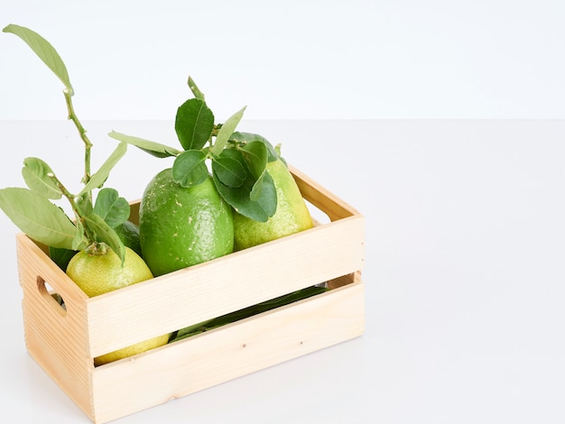 Limones con hojas en caja de madera.