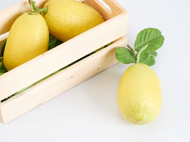 Limones con hojas en caja de madera.