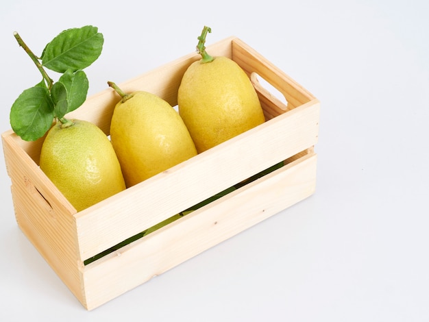 Limones con hojas en caja de madera.