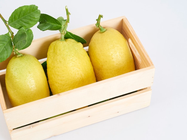 Limones con hojas en caja de madera.