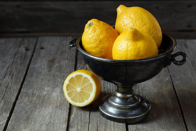 Foto limones en un jarrón de metal sobre una mesa de madera gris