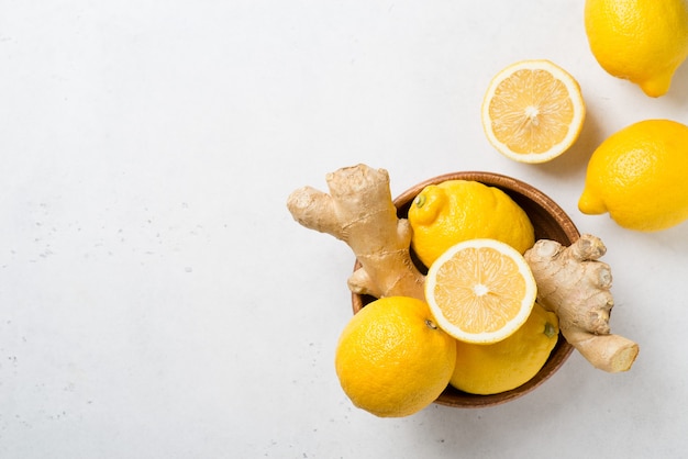 Foto limones y jengibre en un tazón sobre un fondo blanco. vista superior