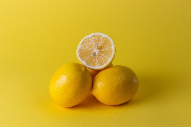 Limones jugosos maduros hojas naranjas y verdes sobre fondo amarillo brillante Fruta de limón cítricos concepto mínimo vitamina C Fondo minimalista de verano creativo Espacio de copia de vista superior endecha plana