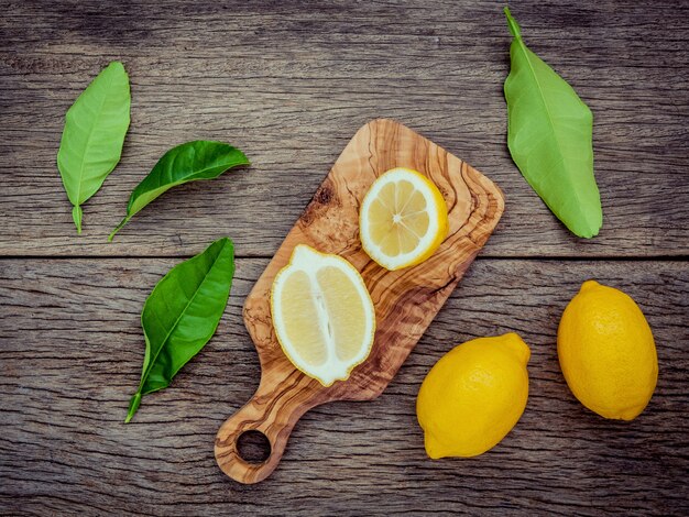 Limones y limones frescos hojas sobre fondo de madera rústica.