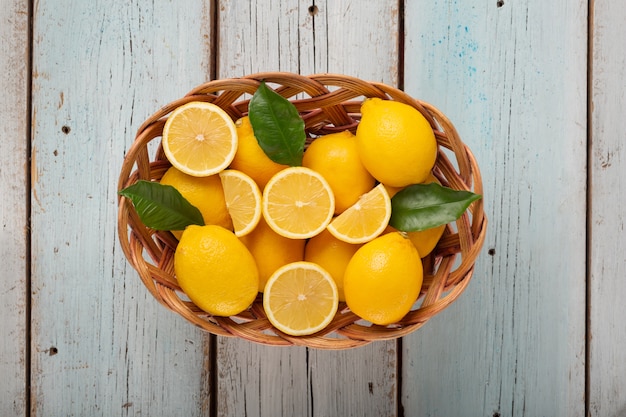 Limones maduros en una cesta de mimbre sobre un fondo de madera azul