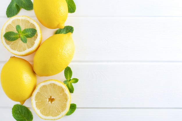 Limones y menta sobre fondo blanco de madera.