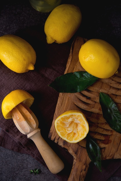 Limones orgánicos jugosos maduros sobre una tabla de madera, fondo oscuro, vista superior