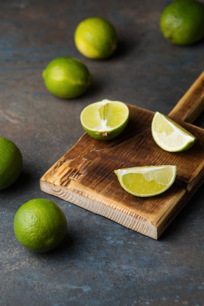 Limones sobre un fondo oscuro Las frutas verdes se cortan en una tabla de madera Lima jugosa Orgánica y saludable