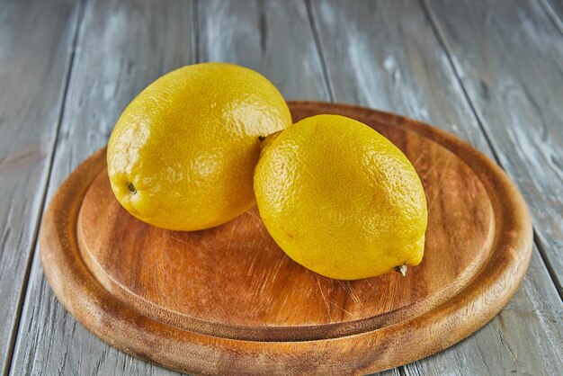 Limones en soporte de madera sobre fondo de madera gris