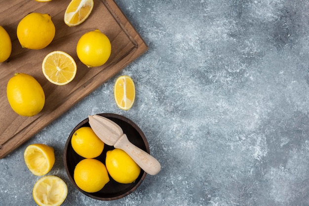 Limones en la tabla de cortar en un tazón en rodajas y fondo gris mezclado completo