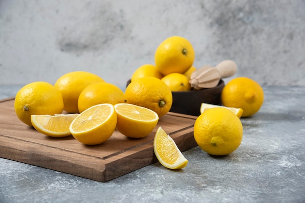 Limones en la tabla de cortar en un tazón en rodajas y fondo gris mezclado completo