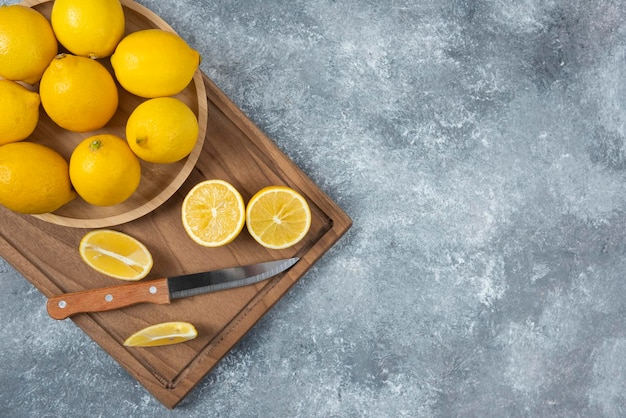 Limones en tazón de madera con tabla de cortar