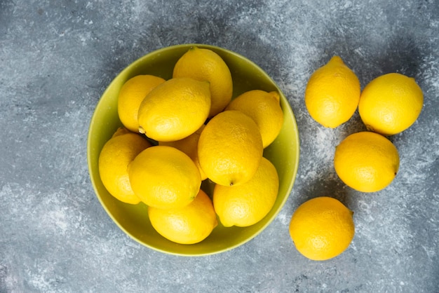 Limones en un tazón sobre fondo gris