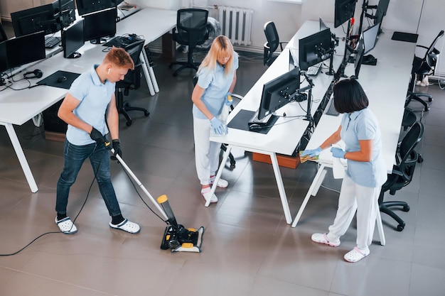 Foto limpa o chão grupo de trabalhadores limpa escritório moderno juntos durante o dia