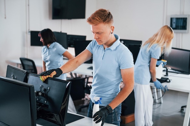 Limpa o monitor Grupo de trabalhadores limpam o escritório moderno juntos durante o dia