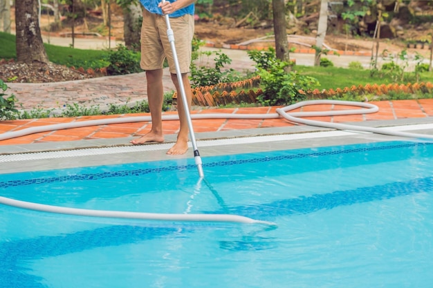 Foto limpador de piscina homem de camisa azul com equipamento de limpeza para piscina ensolarada