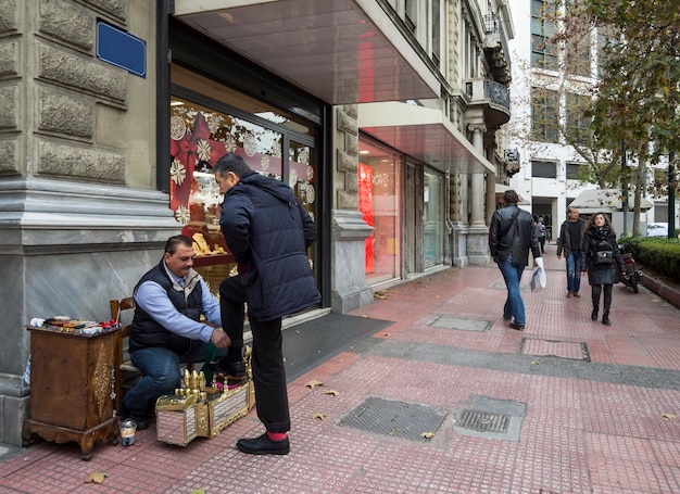 Limpador de sapatos limpa os sapatos dos homens na rua kolonaki distrito em atenas grécia