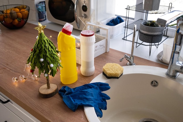 Limpando a cozinha antes dos feriados de Natal e Ano Novo Luvas de esponja de detergente em pó seco estão na pia Decoração festiva na cozinha branca interior aconchegante da casa