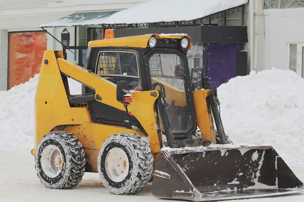 Limpando a neve da estrada com uma escavadeira na cidade no inverno, paisagem urbana