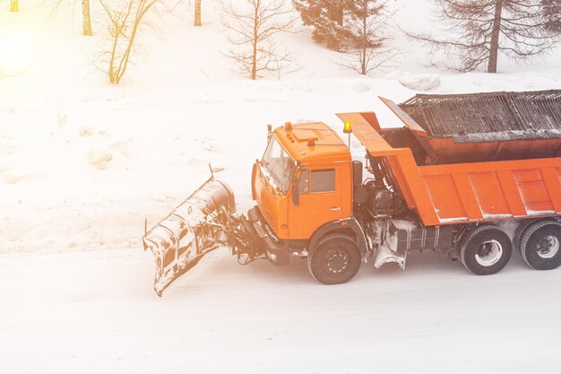 Limpando as estradas da cidade da neve no inverno. Um carro grande está dirigindo e limpando a neve