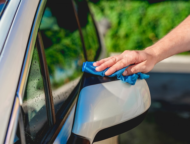 Limpando as mãos do espelho do carro com pano