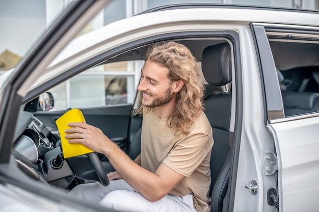 Limpando o carro. jovem homem da máquina limpando o carro e parecendo envolvido