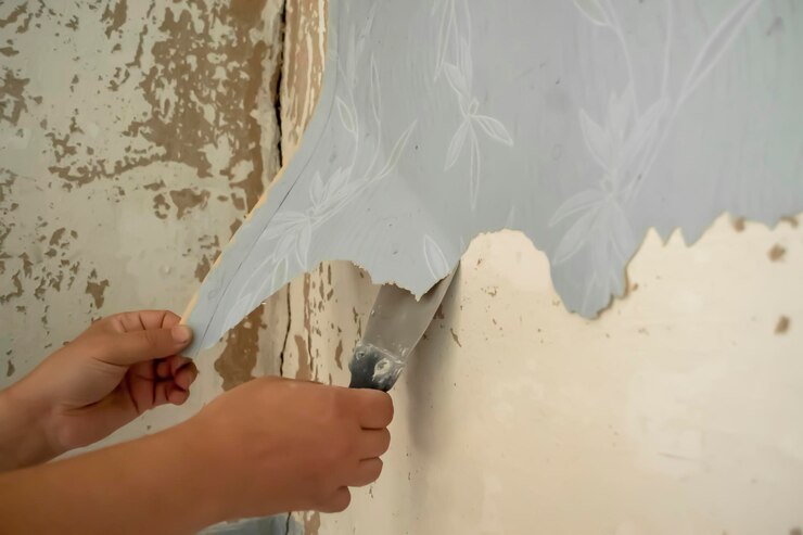 Foto limpando o papel de parede antigo o papel de parede antigo é removido da parede com uma espátula as mãos do homem arrancam o papel de parede da parede