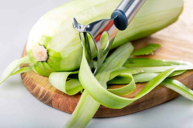 Foto limpando uma abobrinha na cozinha. preparou um prato com legumes, casca de abóbora. dieta crua do conceito verde.